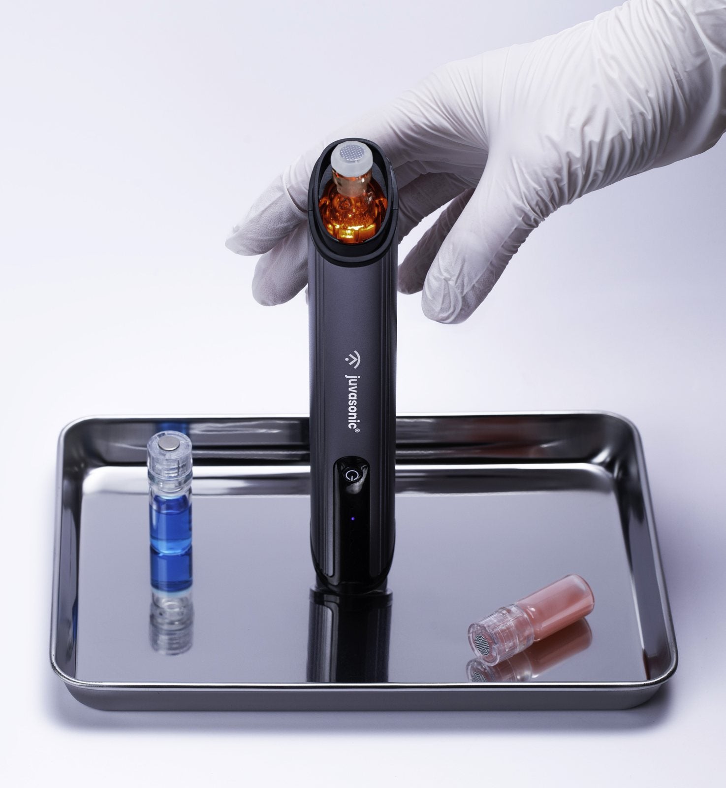 The Juvasonic handheld device on a stainless steel tray